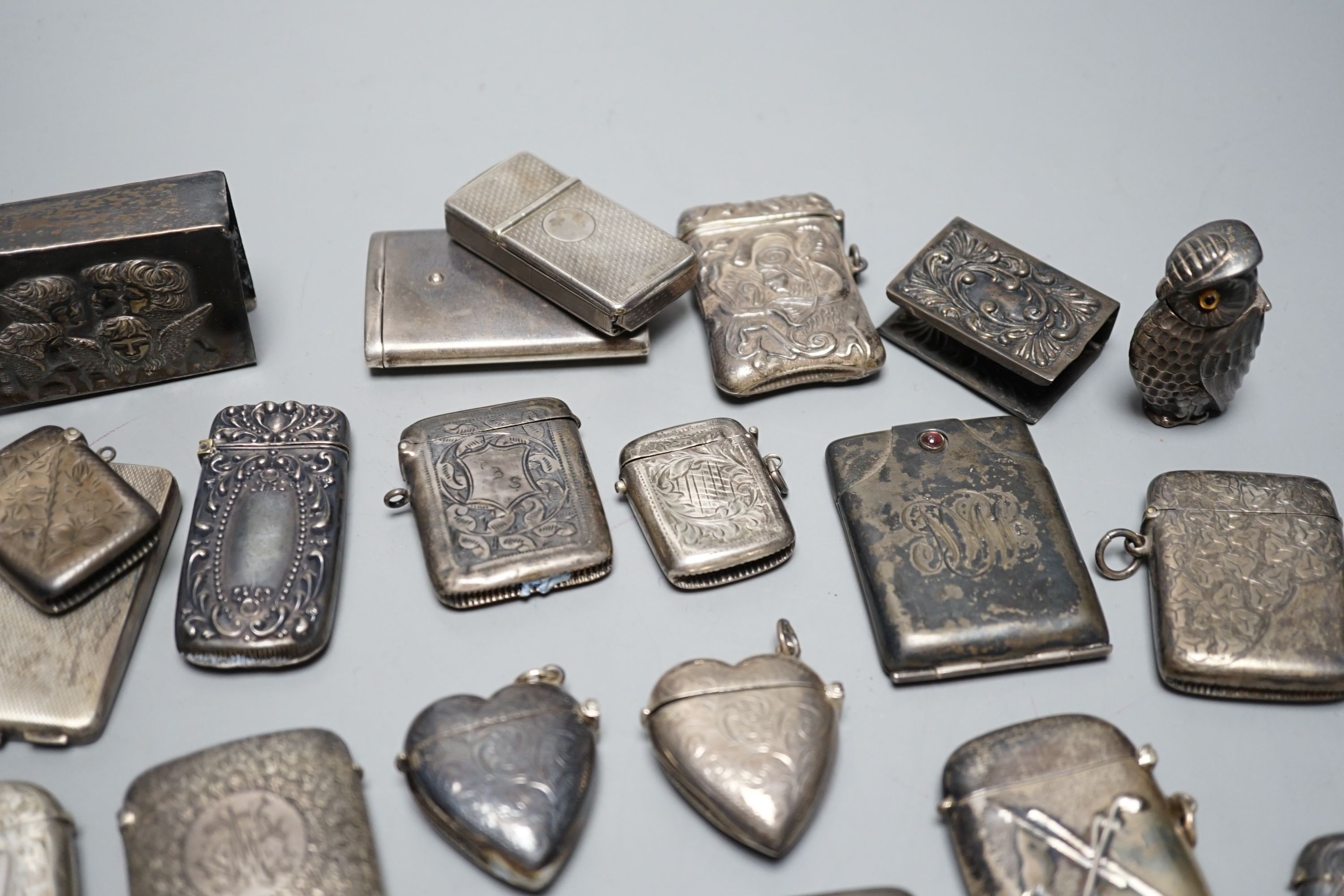 A collection of twenty six assorted mainly early 20th century silver or white metal vesta cases, including heart shape and combination vesta and cheroot cutter, largest 61mm and and seven assorted match cases or sleeves.